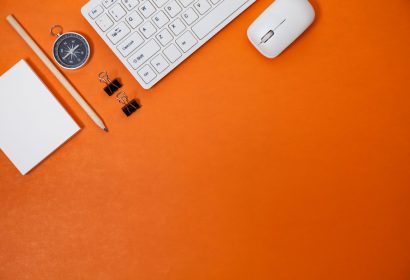 Office desk table of Business workplace and business objects of keyboard,mouse,white paper,notebook,pencil,compass on orange background